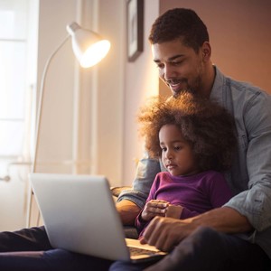 African american dad and his daughter using laptop together.