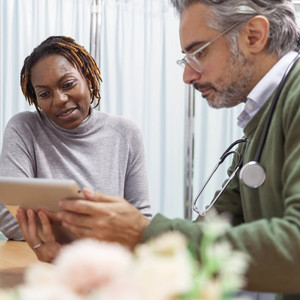 A female patient reviews medical test results with her male doctor. They are seated next to each other