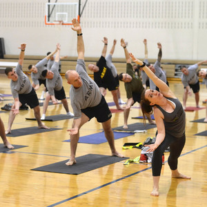 Members of the Army practicing yoga in a gymnasium