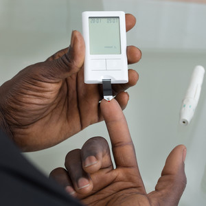 Close-up Of Patient Hands Measuring Glucose Level Blood Test With Glucometer