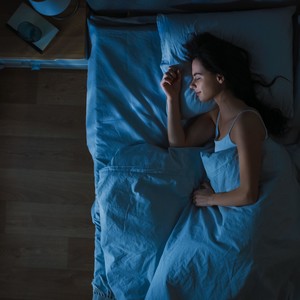 Top View of Young Woman Sleeping Cozily on a Bed in His Bedroom at Night. 
