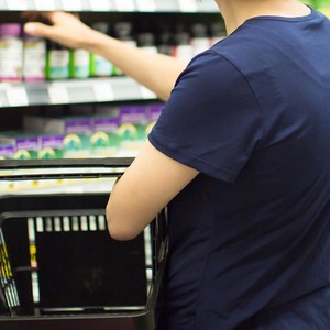 Hand reaching into vitamin and medicine shelf