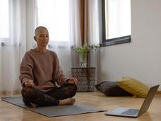 woman sits on a yoga mat in her home