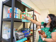 woman selects items from a food pantry shelf