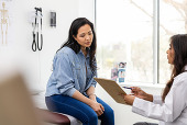 A female patient converses with her health care provider in a professional setting. 