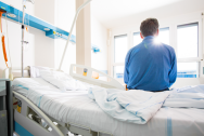 A patient sitting on the a hospital bed, looking outside the window.