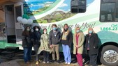 A group of people wearing face masks stand in front of an RV van.