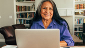 A woman smiles as she sits at her computer.