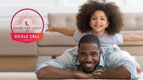 African American Man laying on the floor smiling with his daughter on his back smiling