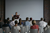 A presenter speaks to a room of people