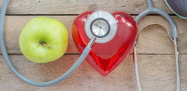 A pair of sneakers, two weights, an apple, a bottle of water, a stethoscope and a heart-shaped box