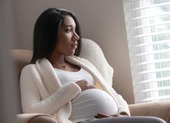 A pregnant woman sitting and looking out a window