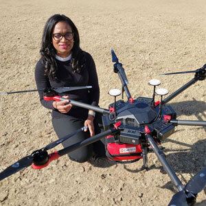 Researcher kneels next to a medical drone equipped with an automated external defibrillator (AED) to help save victims of cardiac arrests. 