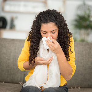 A young woman holds a tissue to her bleeding nose. 