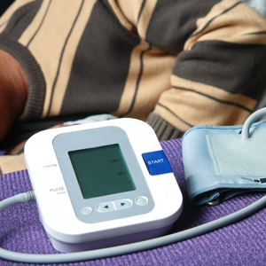 Home blood pressure monitor on side table next to a sleeping person