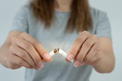 Close-up of a woman breaking a cigarette in two with both hands