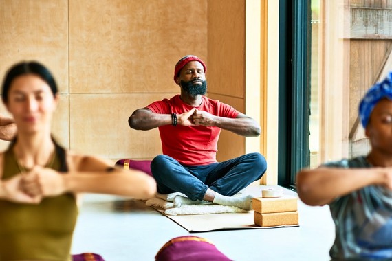 A man sitting cross-legged and meditating in a yoga class