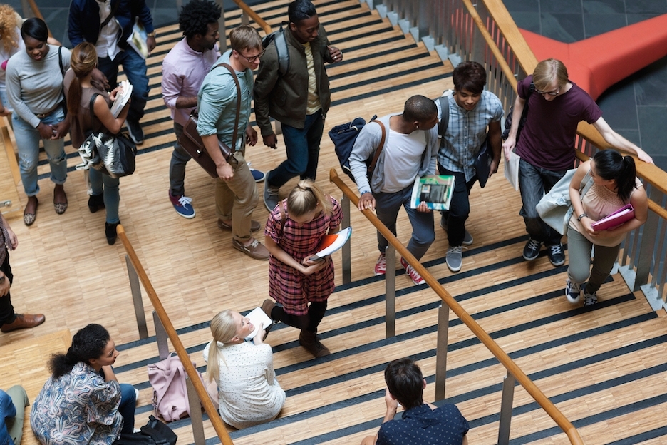 Elevated view of young students walking up and down stairs inside the school.