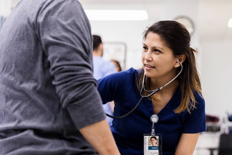 Emergency room practitioner taking vitals of a patient in a clinical setting.