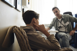 Teenage boy sitting in a medical office and talking with his practitioner.