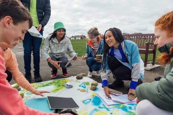 Group of diverse teens outside painting event posters.