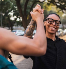 Group of diverse friends great each other and clasp hands while standing in a park. 