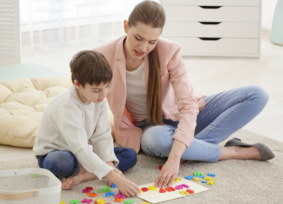 A speech-language pathologist leads a speech-language therapy session with a young boy.