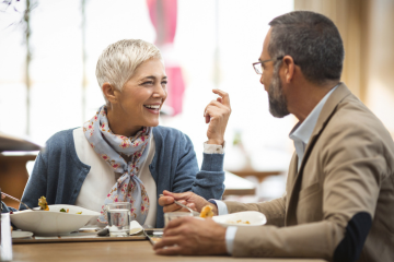 Two older adults talking and laughing in restaurant.