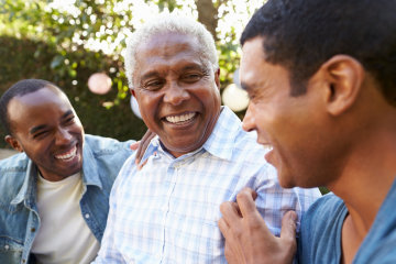 3 men of various ages talking and laughing with each other in a park.