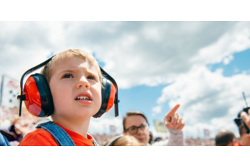 Young child with protective earmuffs at sporting event.