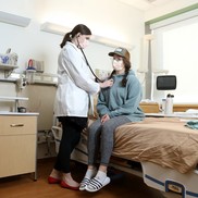 Healthcare worker using stethoscope on patient.