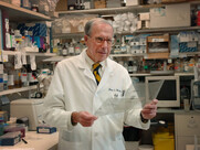 an older man in a research lab wearing a white coat