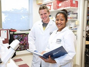 photo of two trainees in a lab in white coats