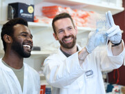 Two people smiling looking at lab equipment