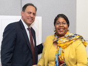 A white man smiling next to a Black woman smiling in a yellow suit