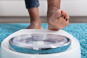 Human foot stepping on weighing scale