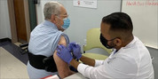 older man receiving vaccination in right shoulder from health care worker