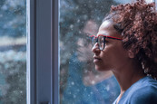 Black woman staring out a window at winter snow  