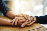 Two hands holding across a table.