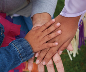 Two African-American adults and one child stacking hands