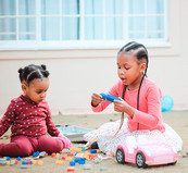 Two young girls sitting on the floor playing with toys