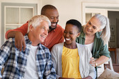 Group of four diverse adults sitting outside a home and laughing. 