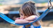 Young child resting against a swing