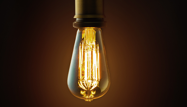 Old-fashioned light bulb shines in the dark.