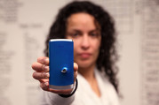 A woman holds a cellphone with a bullet hole in it.