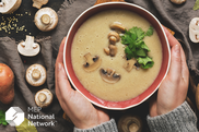 person holding a bowl of soup with mushrooms