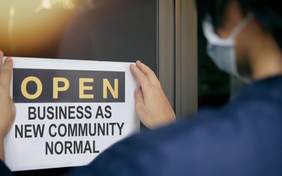 Business owner posting Open Business As New Community Normal sign.