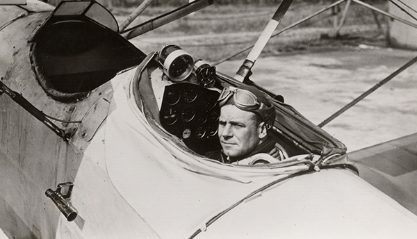 A man (Jimmy Doolittle) sits in an open cockpit of an airplane in a historical photo.