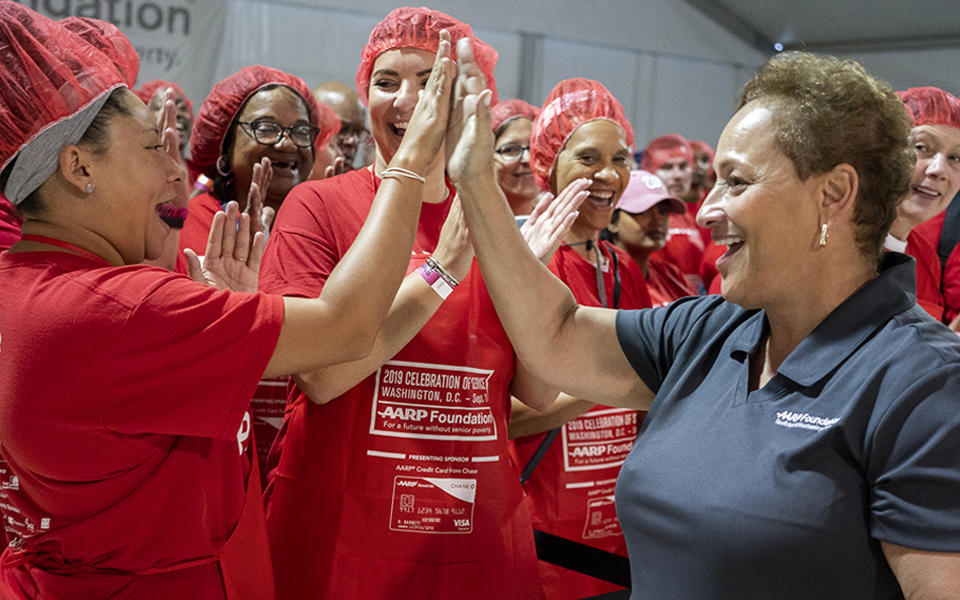 Jo Ann Jenkins, AARP CEO, high-fives a group of volunteers at AARP/AARP Foundation’s fifth annual “Celebration of Service D.C. Meal Pack Challenge”.