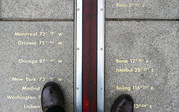 The prime meridian line marker is pictured with a man's shoes in a picture he took looking down. 